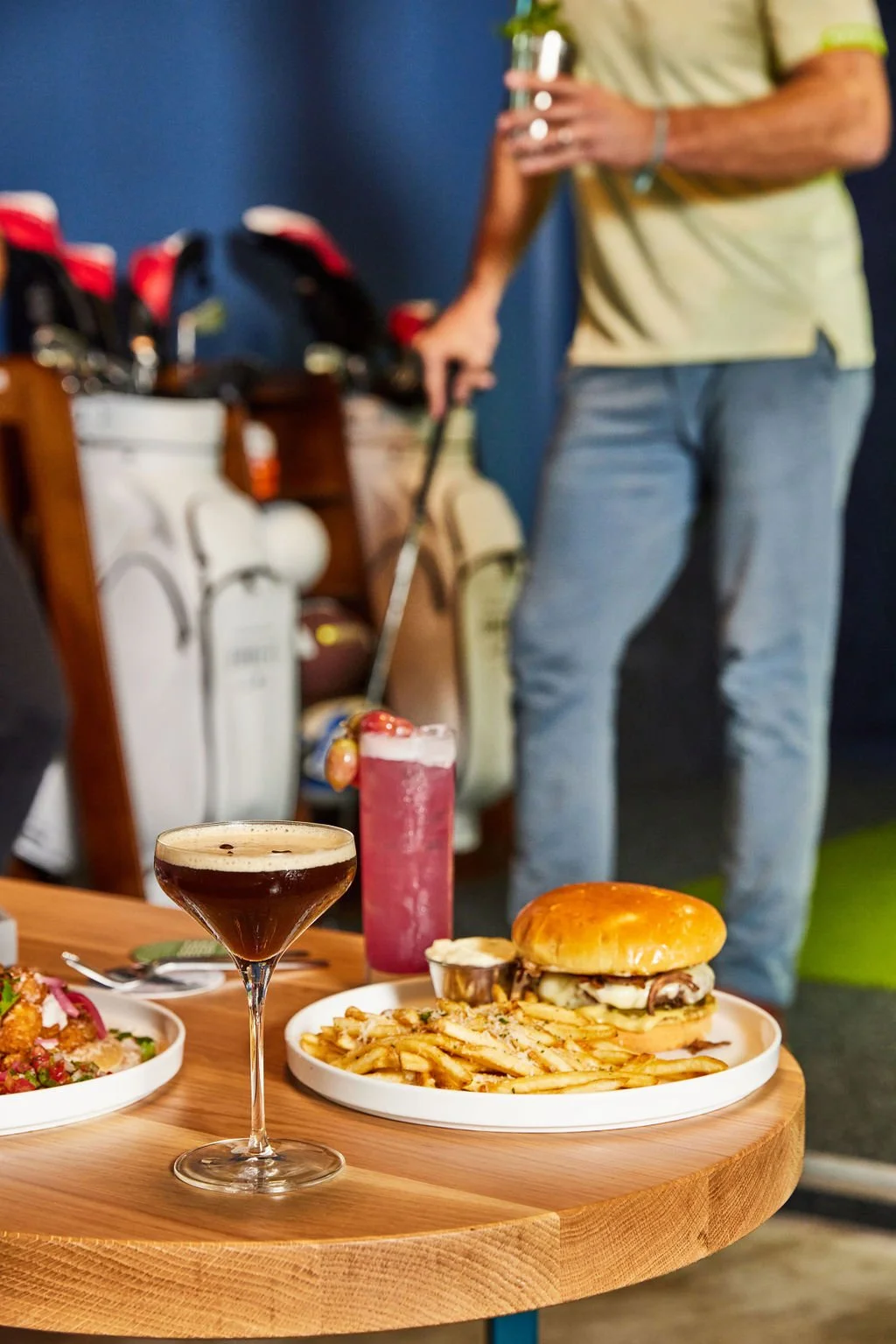 Golf simulator bay at Bunkers with cocktails and a burger